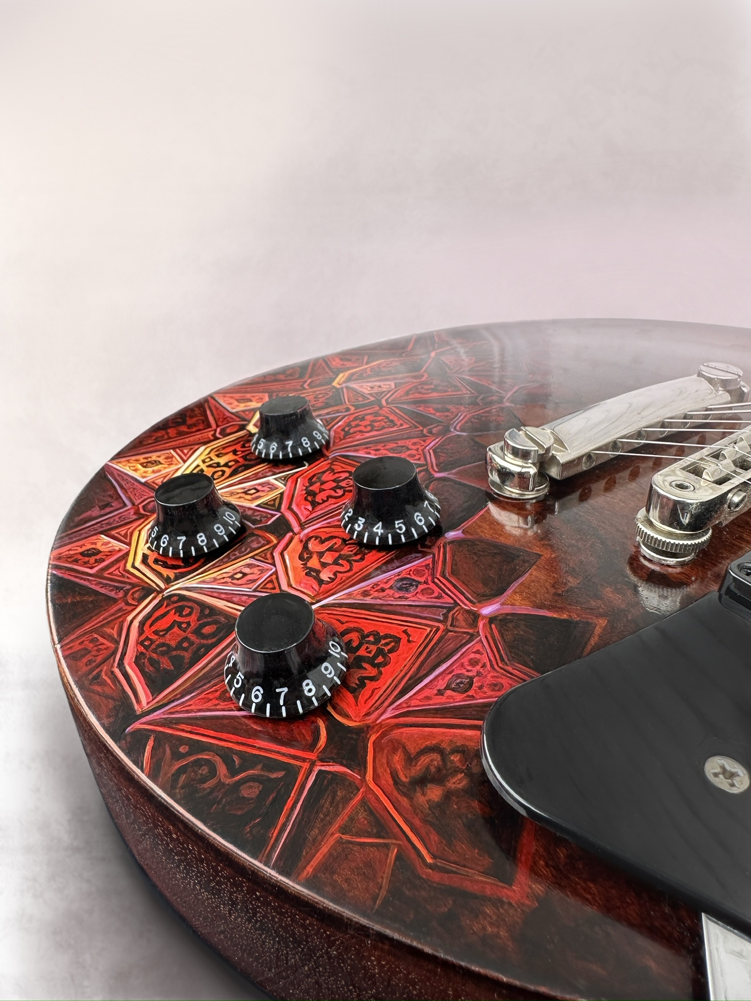 Close view of Agni’s red, orange and black geometric painting around the guitar controls.