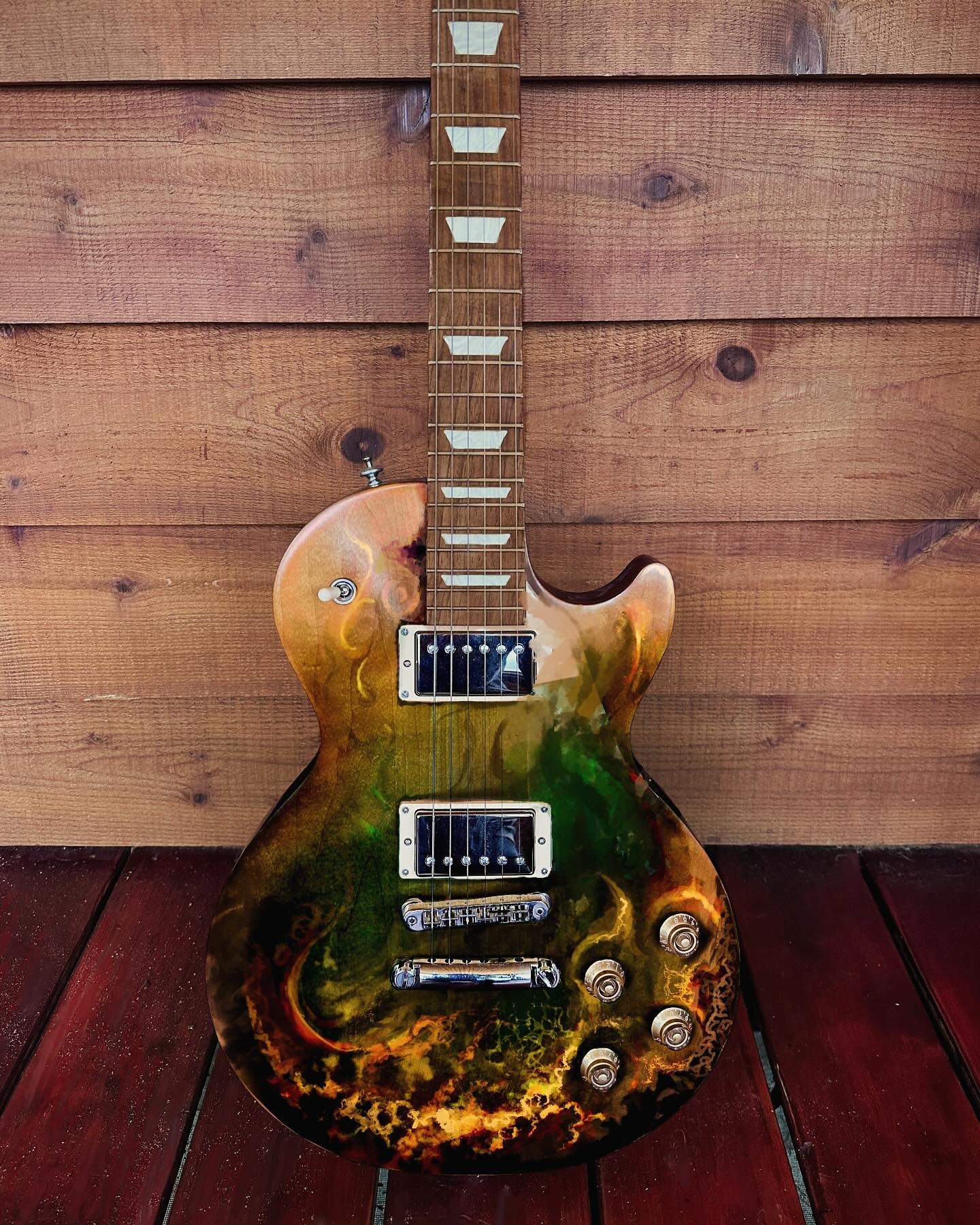 Full electric guitar painted with a dark organic composition in gold, green, red and black.