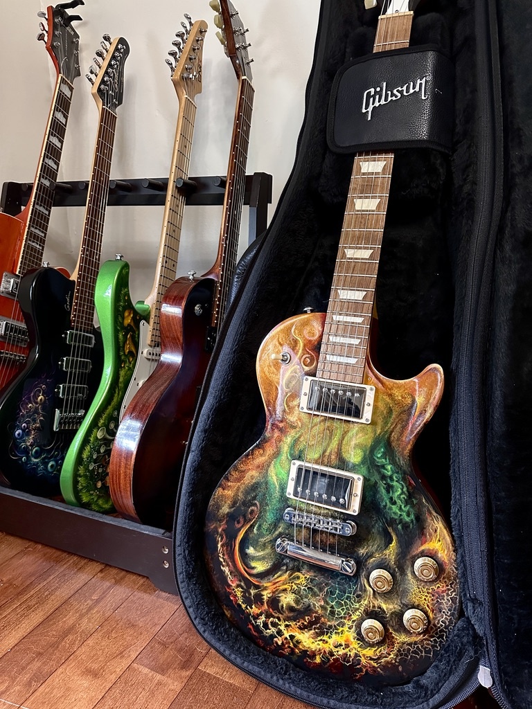 A studio rack holding several distinct hand-painted electric guitars.