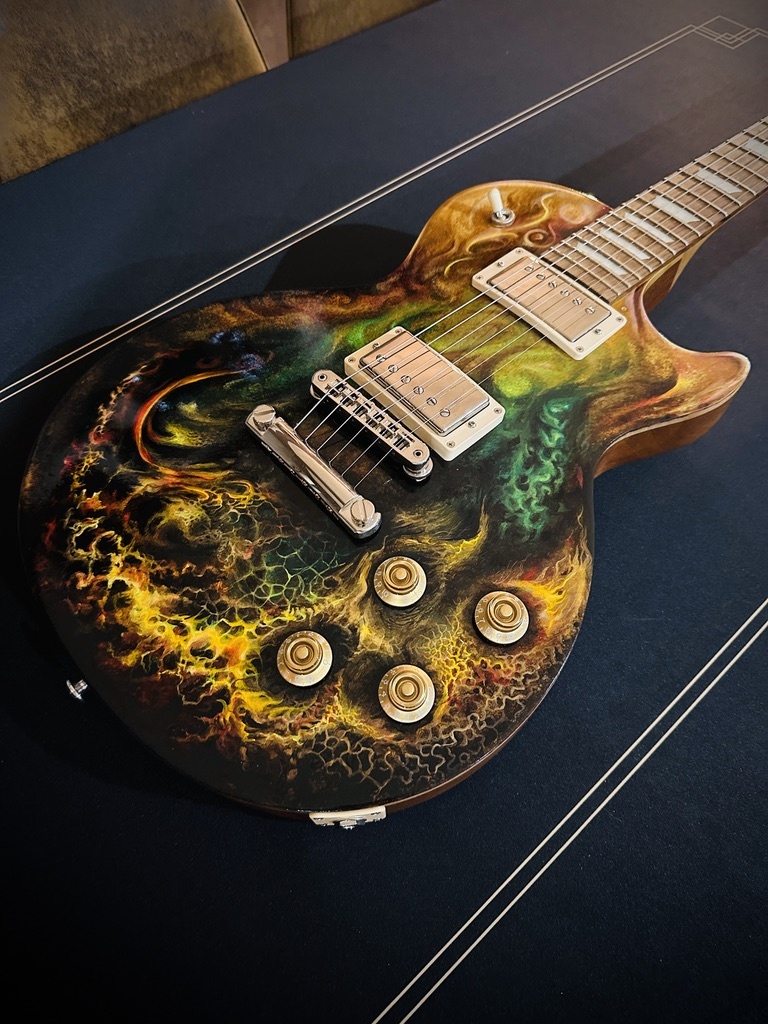 A completed hand-painted guitar resting in its case after finishing.