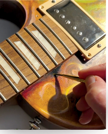 A hand painting detailed colour directly onto an electric guitar body.